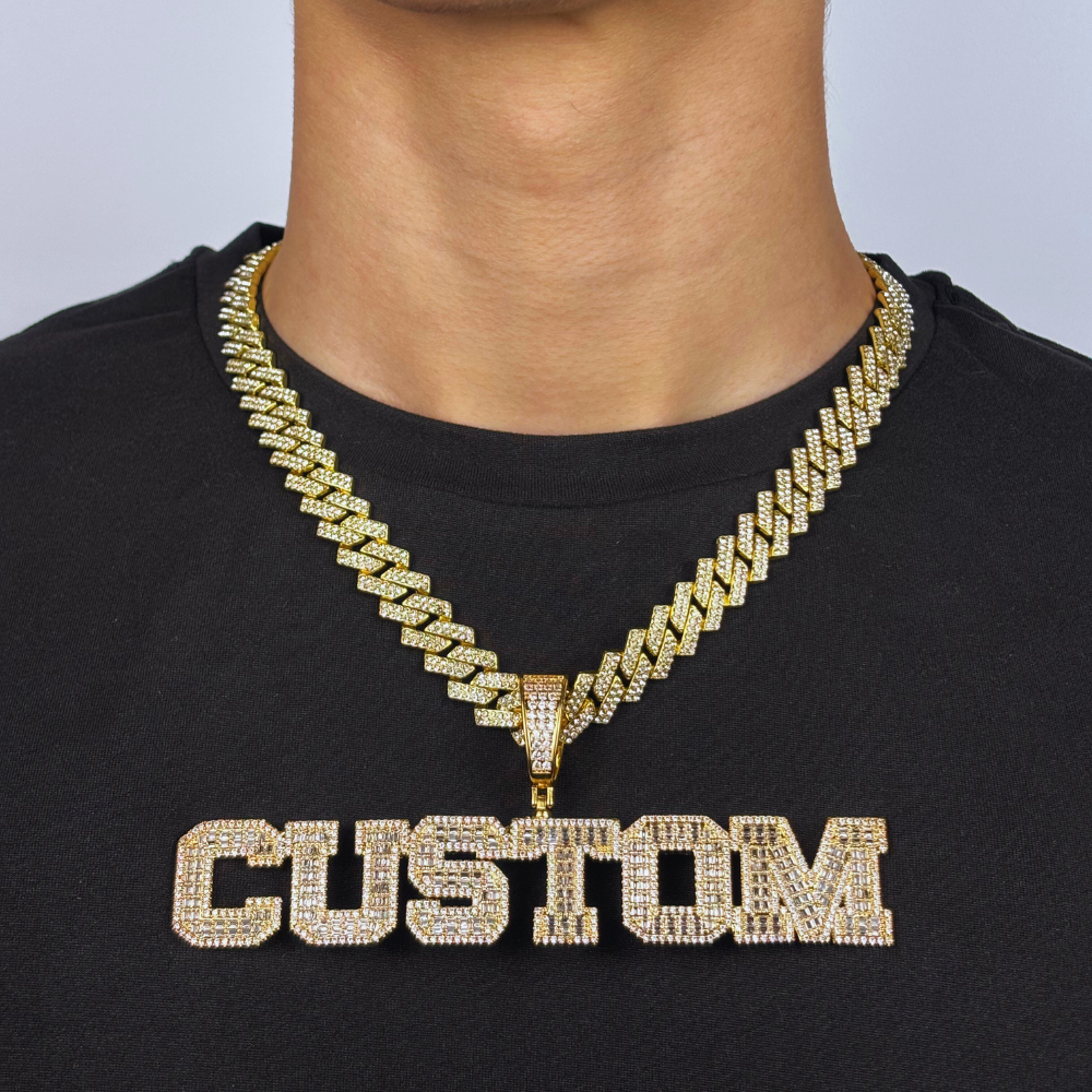 Modelo usa um pendente em forma de letra com design block, cravejado com zircónias cúbicas em ouro dourado, combinando elegância personalizada e brilho sofisticado.