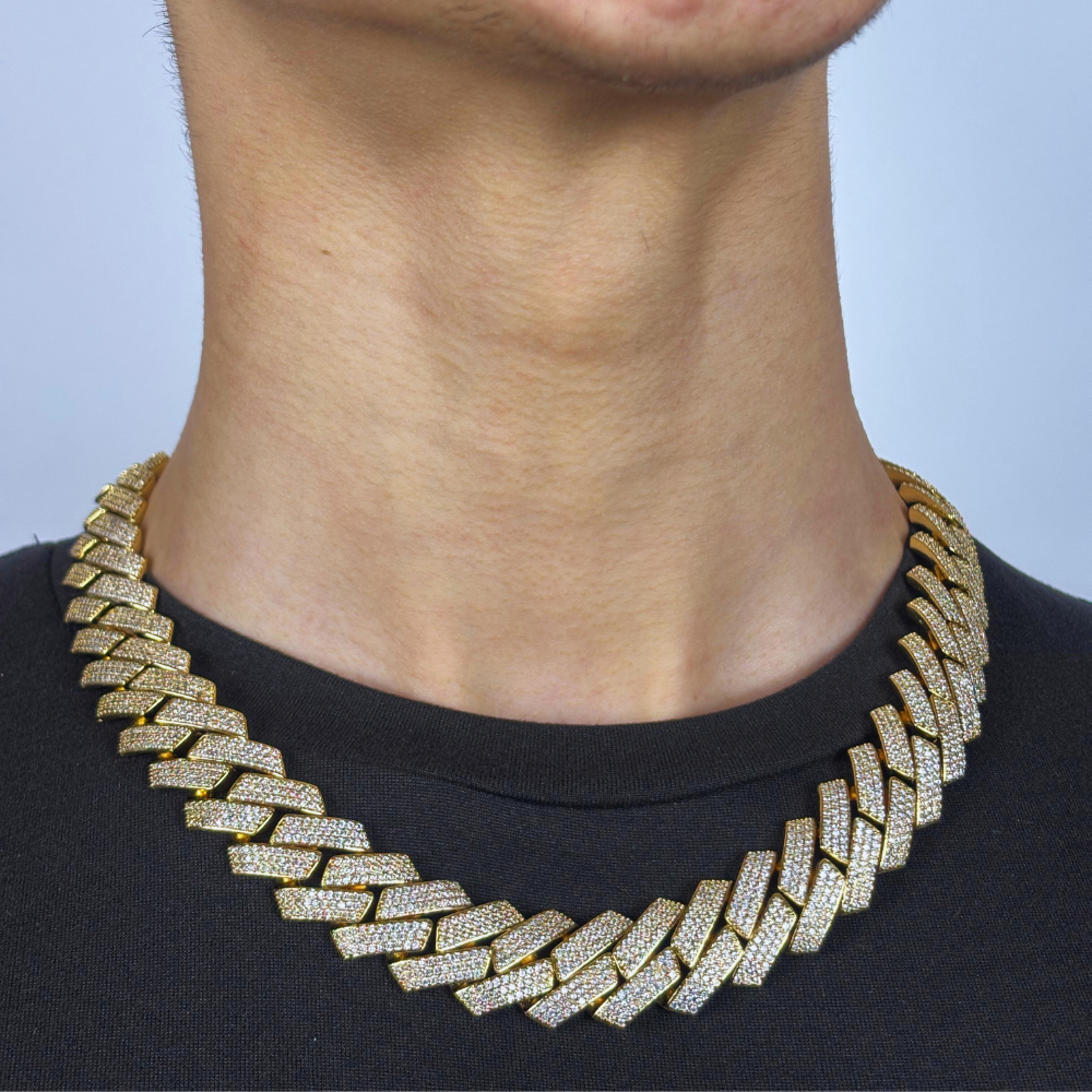 Modelo a exibir o colar 19mm Diamond Prong Link Chain em ouro, com elos robustos e elegantes, cada um delicadamente prateado com diamantes, criando um visual sofisticado e brilhante. O design moderno e luxuoso do colar é perfeito para adicionar um toque de glamour e sofisticação a qualquer look.
