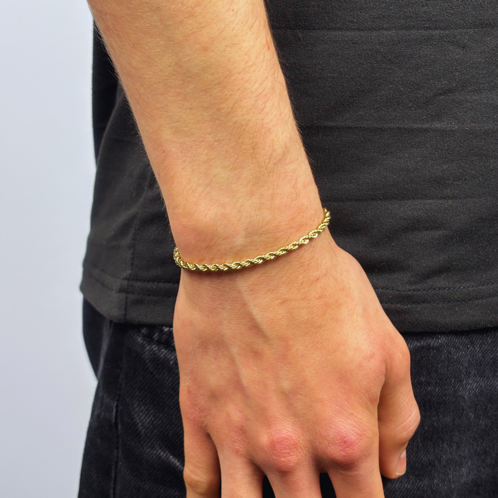 Modelo a usar a pulseira 3mm Rope em ouro, com um design entrelaçado e elegante que cria um visual sofisticado e atemporal. O acabamento polido em ouro proporciona um brilho sutil, tornando a pulseira uma peça versátil e perfeita para adicionar um toque de luxo discreto a qualquer estilo.