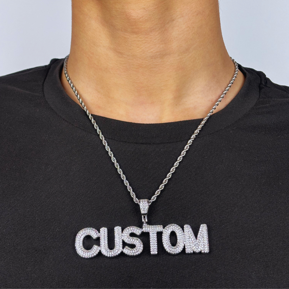 Modelo usa um pendente personalizado em ouro branco com zircónias cúbicas, em estilo bold e acabamento ice, destacando-se pelo brilho intenso e design marcante.